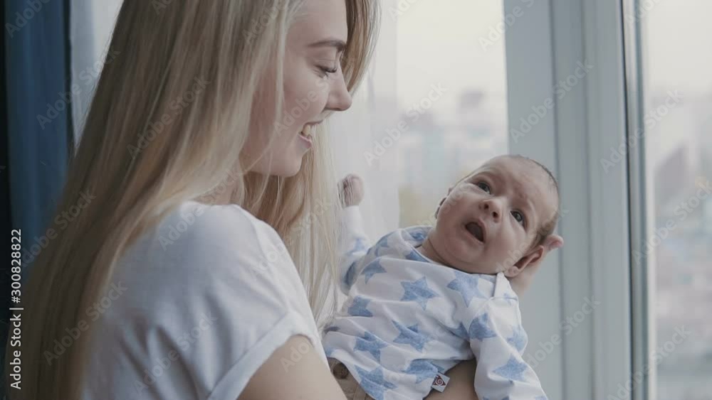 Happy young family - young mother holding her new born son, kissing and hugging. Happy family concept. Slowmotion video. Happy young family - young mother holding her new born son, kissing and hugging. Happy family concept. Slowmotion video.