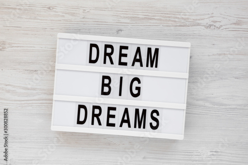 'Dream big dreams' words on a lightbox on a white wooden background, top view. Overhead, from above, flat lay.