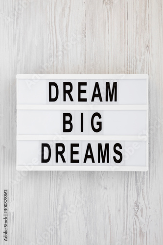 'Dream big dreams' words on a modern board on a white wooden surface, top view. Overhead, from above, flat lay.