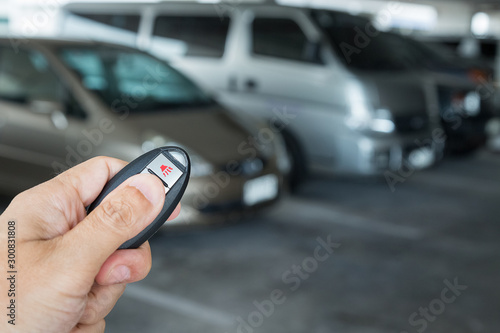 Hand holding car key remote at car park