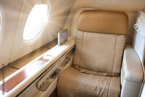 Business or first class seat of the airline have brown color near windows with sun light.They feel luxury , comfort and private when travel or work.Jet airplane and commercial are use for transport.