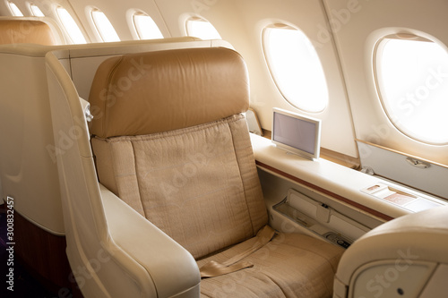 Business or first class seat of the airline have brown color near windows with sun light.They feel luxury , comfort and private when travel or work.Jet airplane and commercial are use for transport.