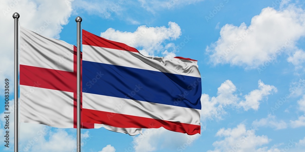 England and Thailand flag waving in the wind against white cloudy blue sky together. Diplomacy concept, international relations.
