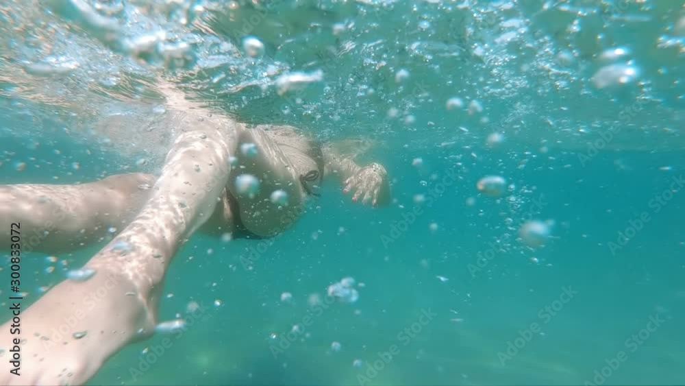 Slow motion of underwater shot of female swimming backwards in the sea Slow motion of underwater shot of female swimming backwards in the sea