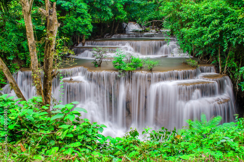 Travel to the beautiful waterfall in tropical rain forest, soft water of the stream in the natural park at Kanchanaburi, Thailand.