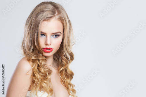 Sensual blonde woman with long healthy curly hair and red lips