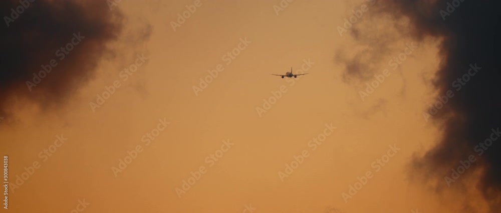 Plane flying into the clouds, at sunset sky. Slow motion, BMPCC 4K. Copy space