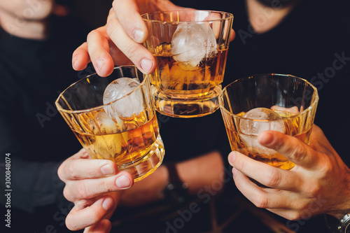 Clinking glasses with alcohol and toasting, party. whiskey ice photo