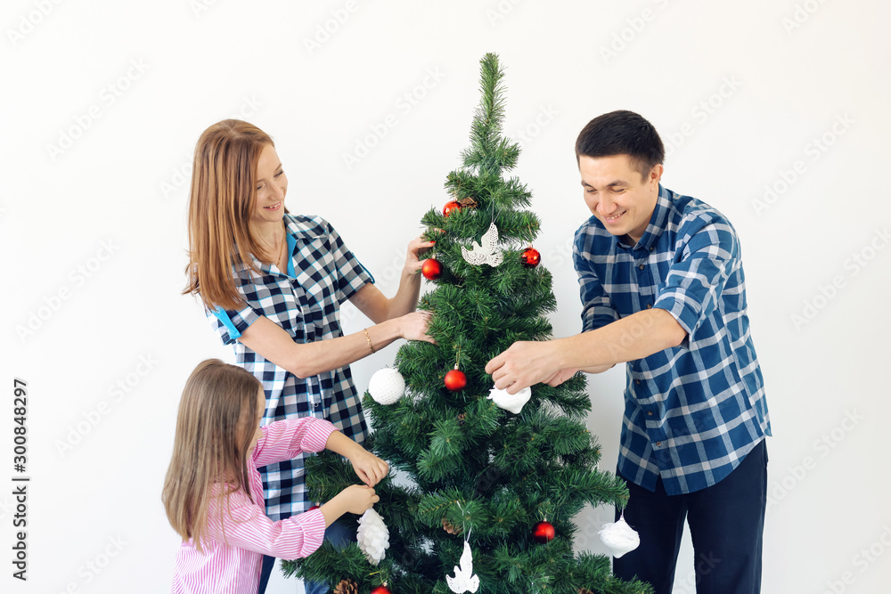 Holidays, x-mas and celebrating concept - Happy family decorating Christmas tree in holiday on white background Holidays, x-mas and celebrating concept - Happy family decorating Christmas tree in holiday on white background