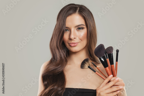 Portrait of beautiful woman with makeup brushes