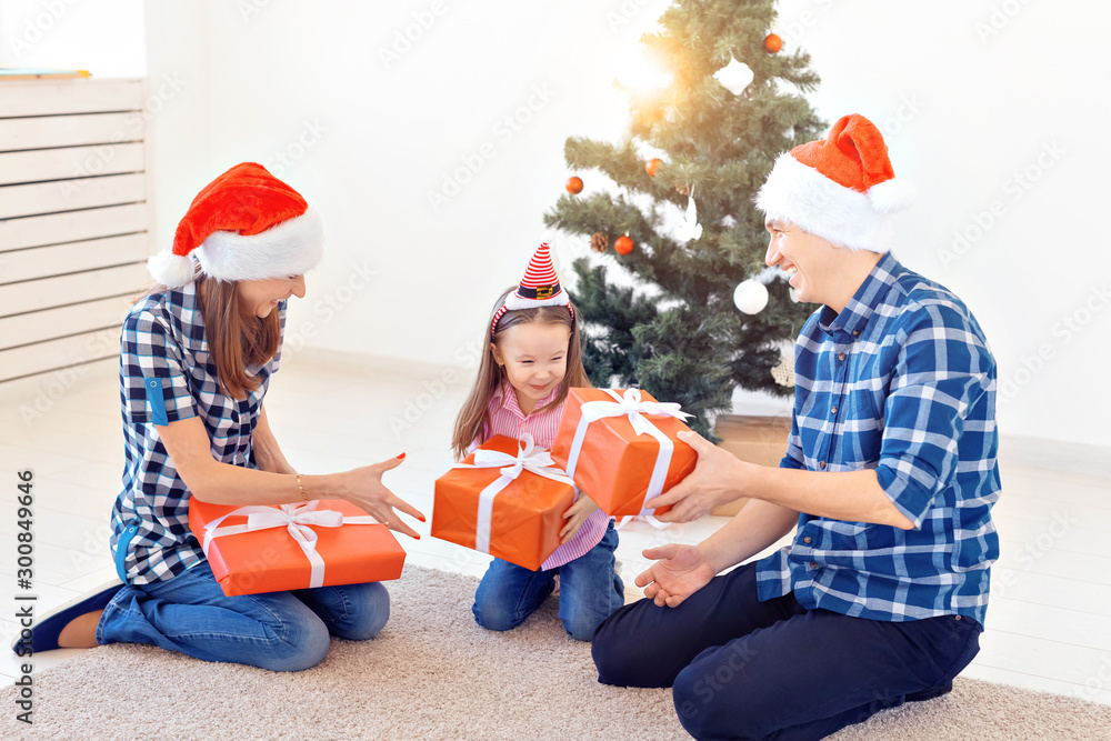 Obraz premium Holidays and presents concept - Portrait of a happy family opening gifts at Christmas time