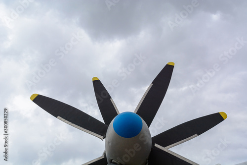 Part of the fuselage of the old military plane with the propeller closeup against the background of an empty and gray sky.