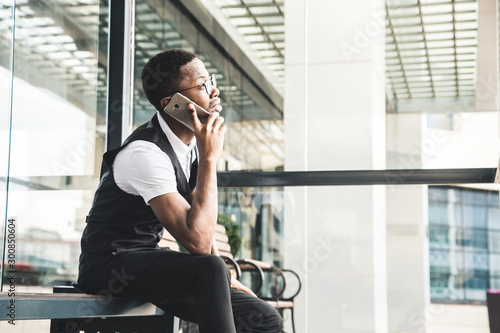Young african american business man in suit and eyeglasses talking on the phone on the background of the business center
