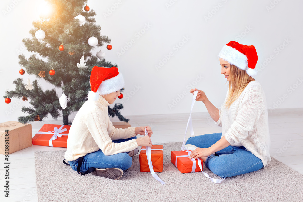 Fototapeta premium Single parent and holidays concept - Portrait of mother and son celebrating christmas at home on christmas eve
