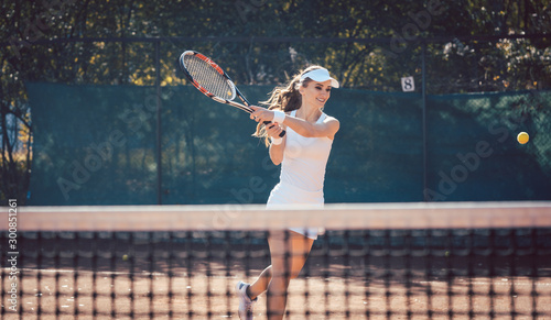 Woman forcefully playing tennis © Kzenon