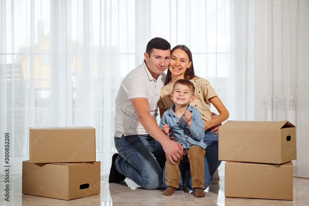 Happy family sitting on the floor in their new house among cardboard boxes. Happy family sitting on the floor in their new house among cardboard boxes.