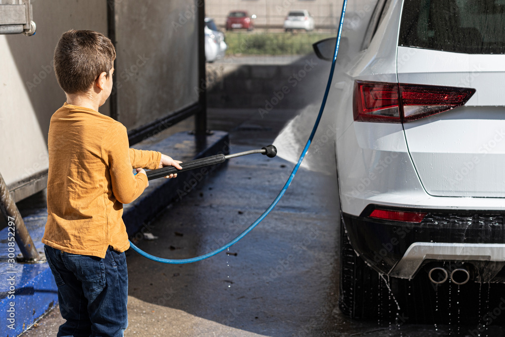 Little kid cleaning a car with a high pressure hose Little kid cleaning a car with a high pressure hose