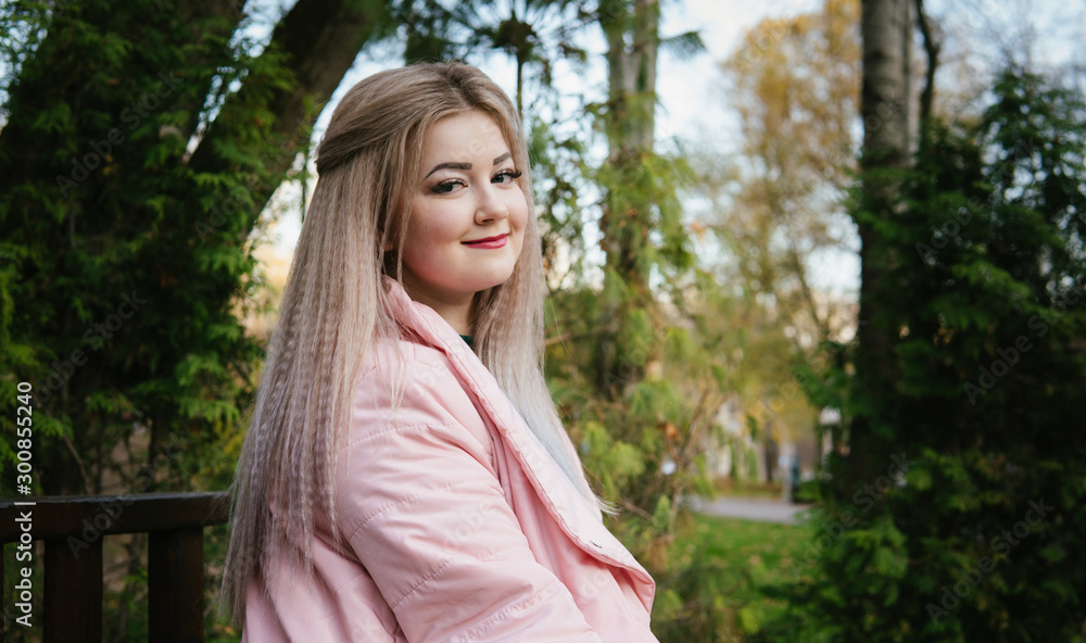 A portrait of a beautiful woman, sitting on a bench near the green vegetation. A portrait of a beautiful woman, sitting on a bench near the green vegetation.