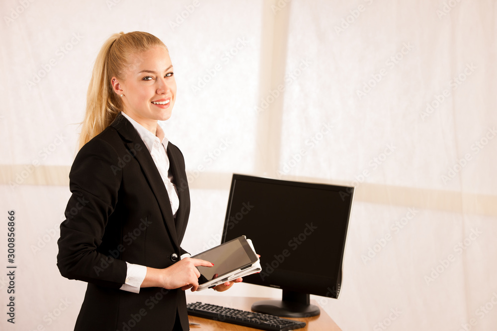 Beautiful young business woman surfing the web on tablet checking data in her office Beautiful young business woman surfing the web on tablet checking data in her office