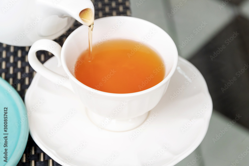Pouring earl grey tea from teapot in a white porcelain cup . Healthy drinks concept. Pouring earl grey tea from teapot in a white porcelain cup . Healthy drinks concept.