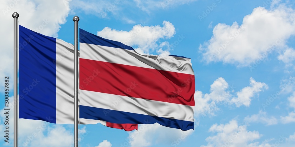 France and Costa Rica flag waving in the wind against white cloudy blue sky together. Diplomacy concept, international relations.