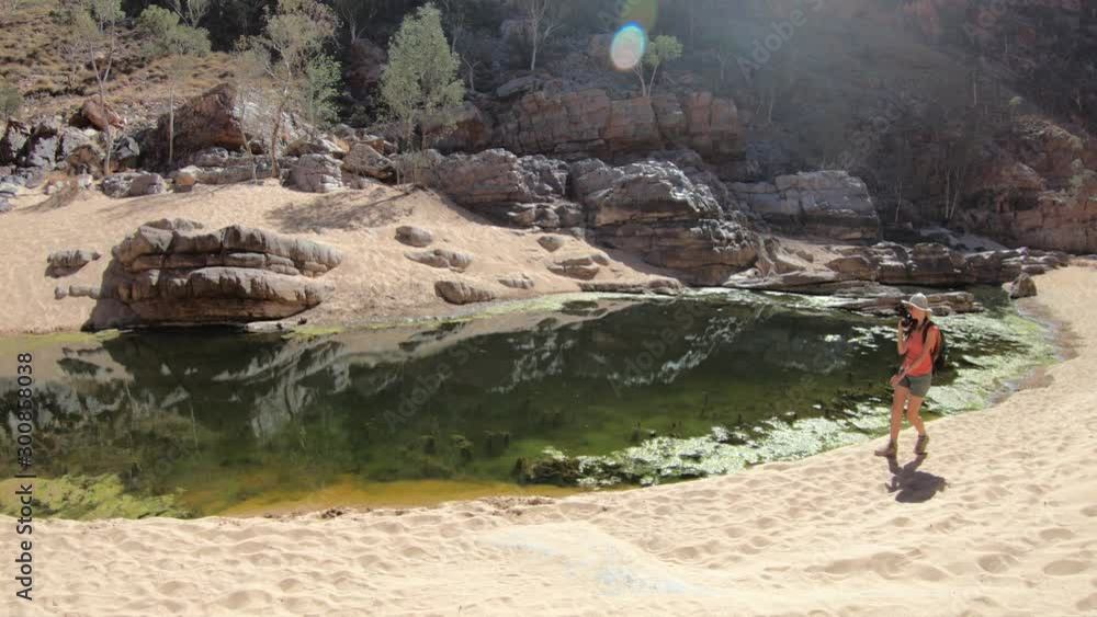 woman photographer in Ormiston Pound Walk, a circuit that follows the rocky slope into of pound and back along the gorge by main waterhole. West MacDonnell Range, Australia, Northern Territory woman photographer in Ormiston Pound Walk, a circuit that follows the rocky slope into of pound and back along the gorge by main waterhole. West MacDonnell Range, Australia, Northern Territory