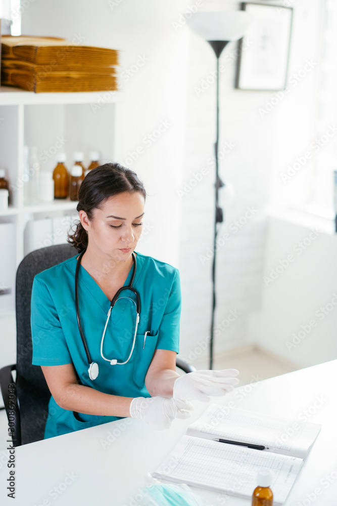 Young female doctor in medical office. Beautiful female doctor putting gloves on. Young female doctor in medical office. Beautiful female doctor putting gloves on.