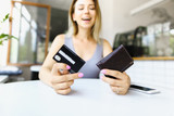 Blonde woman sitting at cafe and keeping wallet with debit card.