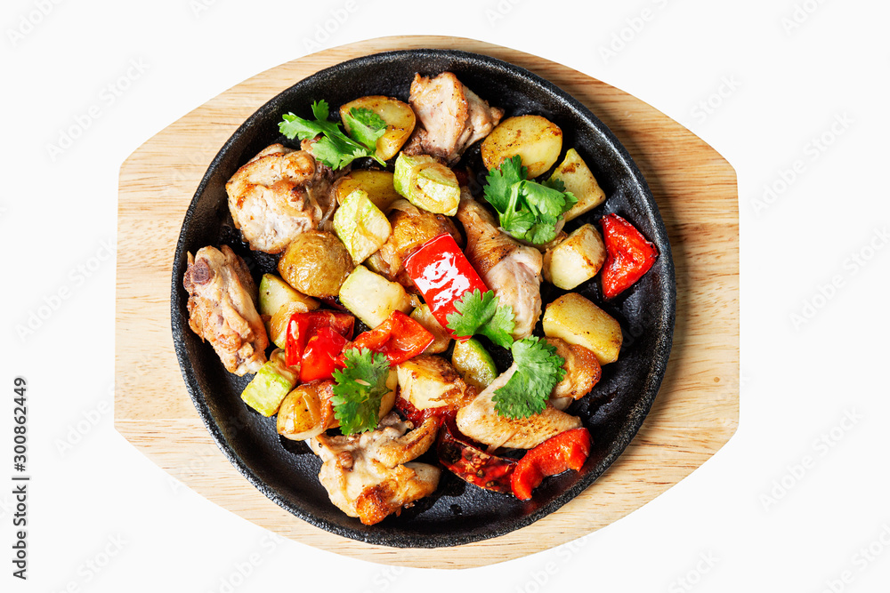 Roasted vegetables on a cast-iron pan served on a wooden board. Top view. Isolated over white background. Roasted vegetables on a cast-iron pan served on a wooden board. Top view. Isolated over white background.
