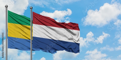 Gabon and Netherlands flag waving in the wind against white cloudy blue sky together. Diplomacy concept, international relations.