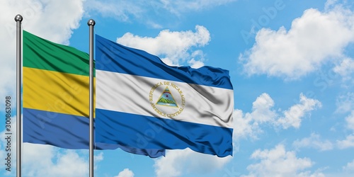 Gabon and Nicaragua flag waving in the wind against white cloudy blue sky together. Diplomacy concept, international relations.