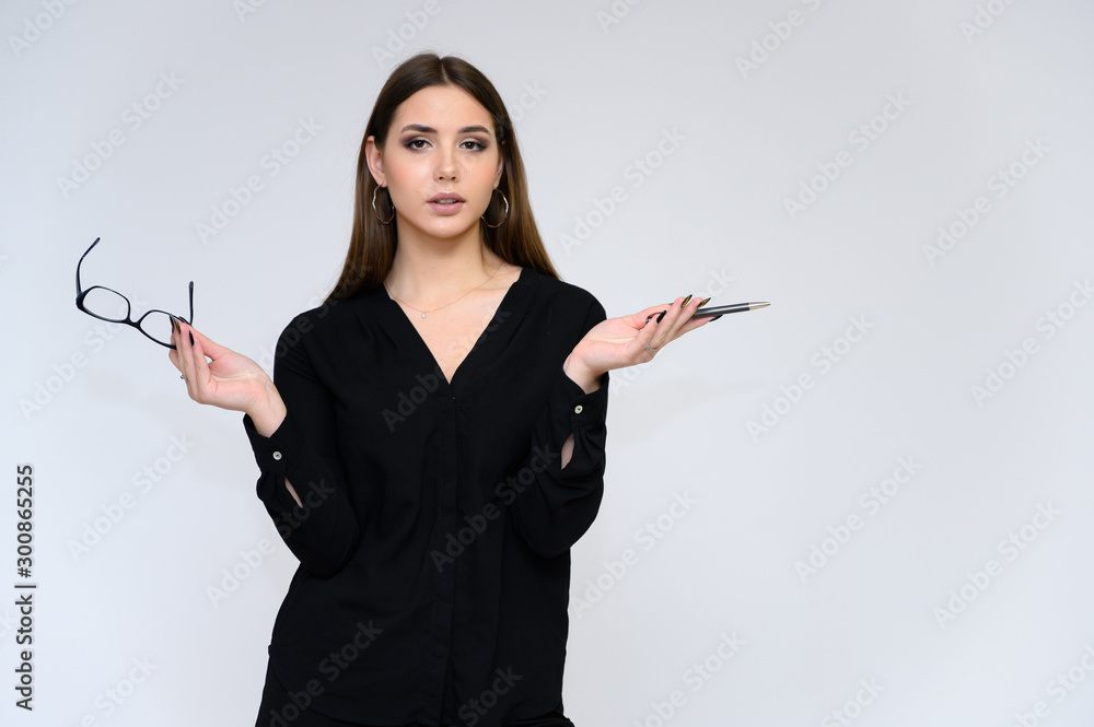 Close-up portrait of a young pretty girl secretary with long black hair in a business suit, on a white background. Standing right in front of the camera in different poses with emotions. Close-up portrait of a young pretty girl secretary with long black hair in a business suit, on a white background. Standing right in front of the camera in different poses with emotions.