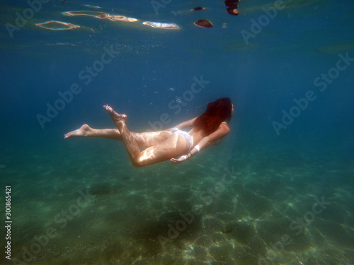Beautiful girl in bikini swimming, floating underwater in the sea © AlfredSS