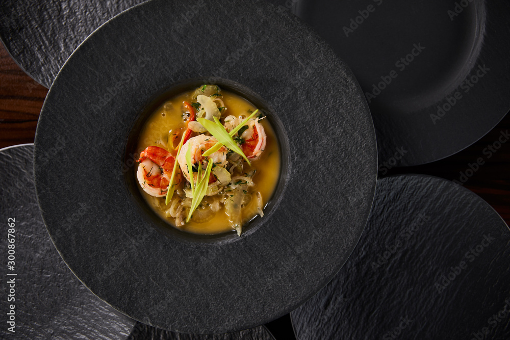 top view of delicious restaurant soup with shrimps in black plate - obrazy, fototapety, plakaty 