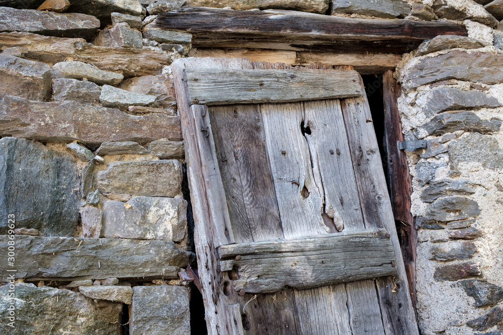 Angled wooden door at the entrance of an abandoned house in the Alps Angled wooden door at the entrance of an abandoned house in the Alps