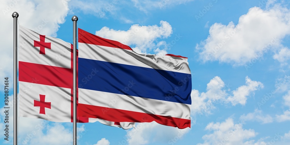 Georgia and Thailand flag waving in the wind against white cloudy blue sky together. Diplomacy concept, international relations.