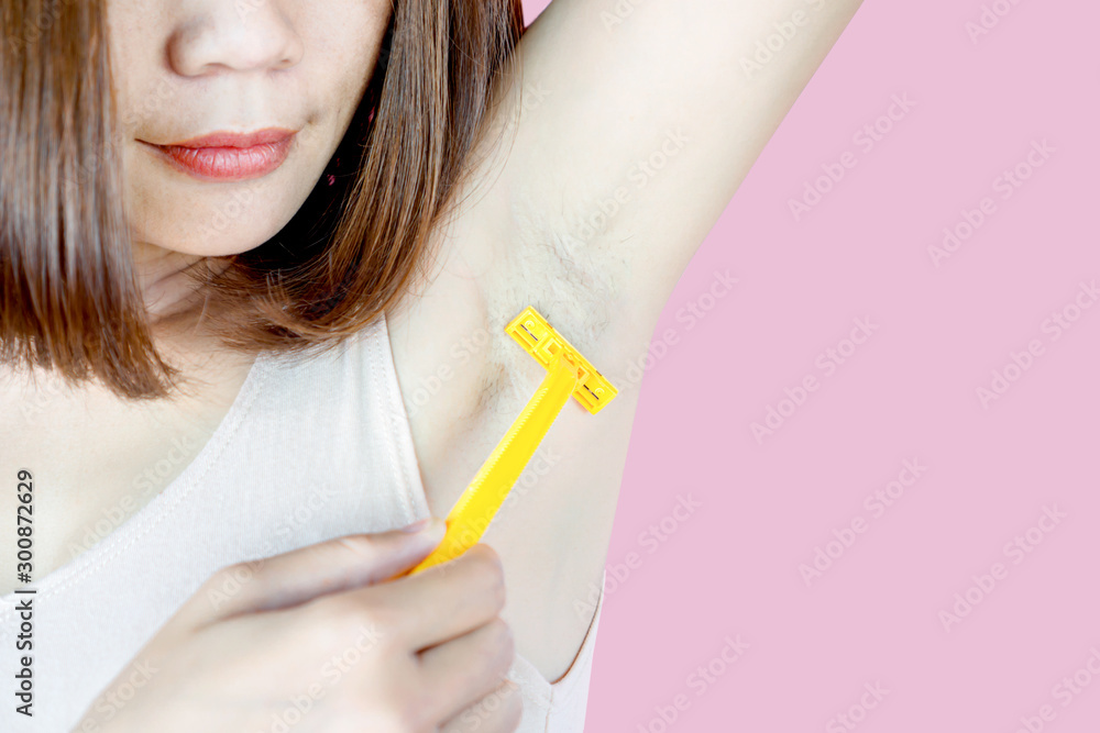 Asian woman using razor shaving hair under armpits Asian woman using razor shaving hair under armpits