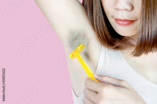 Asian woman using razor shaving hair under black armpit photo