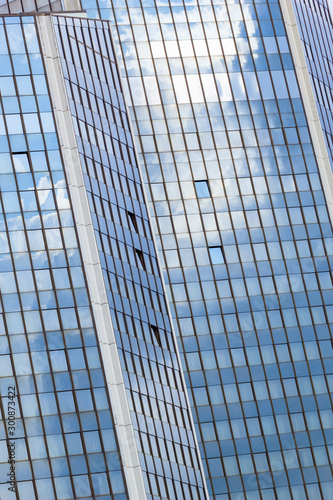 Abstract fragment of modern business architecture made of glass and steel with reflection of blue sky and clouds