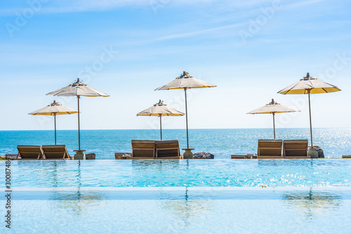 Beautiful landscape of sea ocean on sky with umbrella and chair around luxury outdoor swimming pool