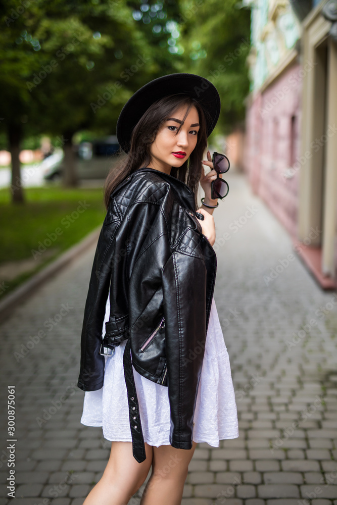 Naklejka premium Beauty on the go. Rear view of attractive young asian woman looking away while walking down the street outdoors