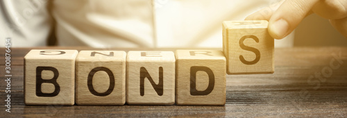 Businessman puts wooden blocks with the word Bonds. A bond is a security that indicates that the investor has provided a loan to the issuer. Equivalent loan. Unsecured and secured bonds. photo