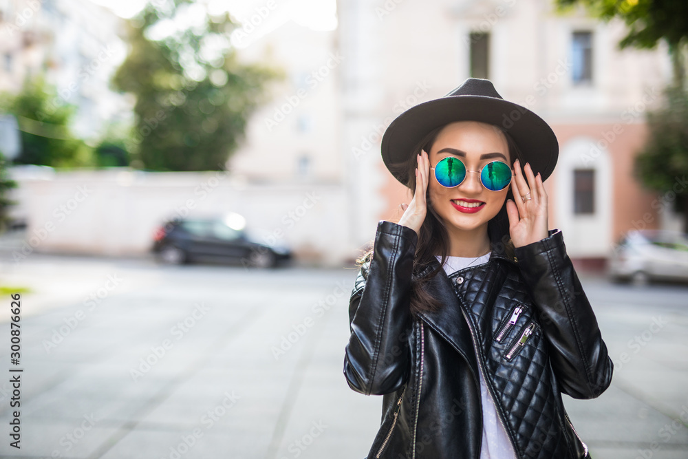 Smiling asian woman standing with sunglasses on city street. Smiling asian woman standing with sunglasses on city street.