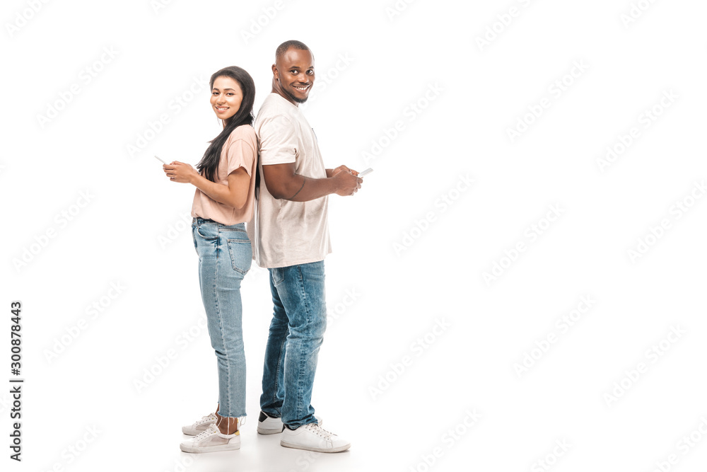 smiling african american couple standing back to back and using smartphones on white background smiling african american couple standing back to back and using smartphones on white background