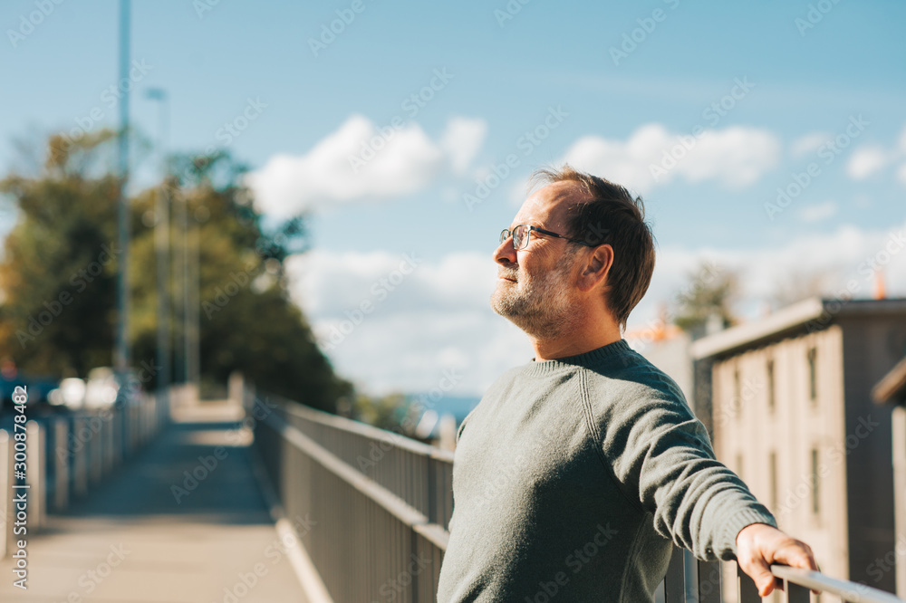 Outdoor portrait of 50 - 55 year old man wearing green pullover and eyeglasses Outdoor portrait of 50 - 55 year old man wearing green pullover and eyeglasses