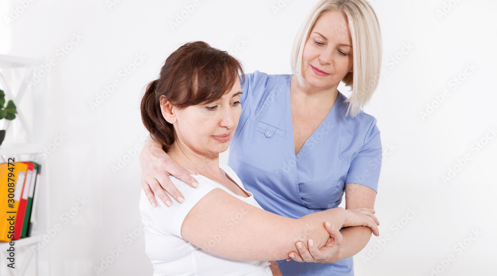Physiotherapist working with middle aged patient in clinic Physiotherapist working with middle aged patient in clinic