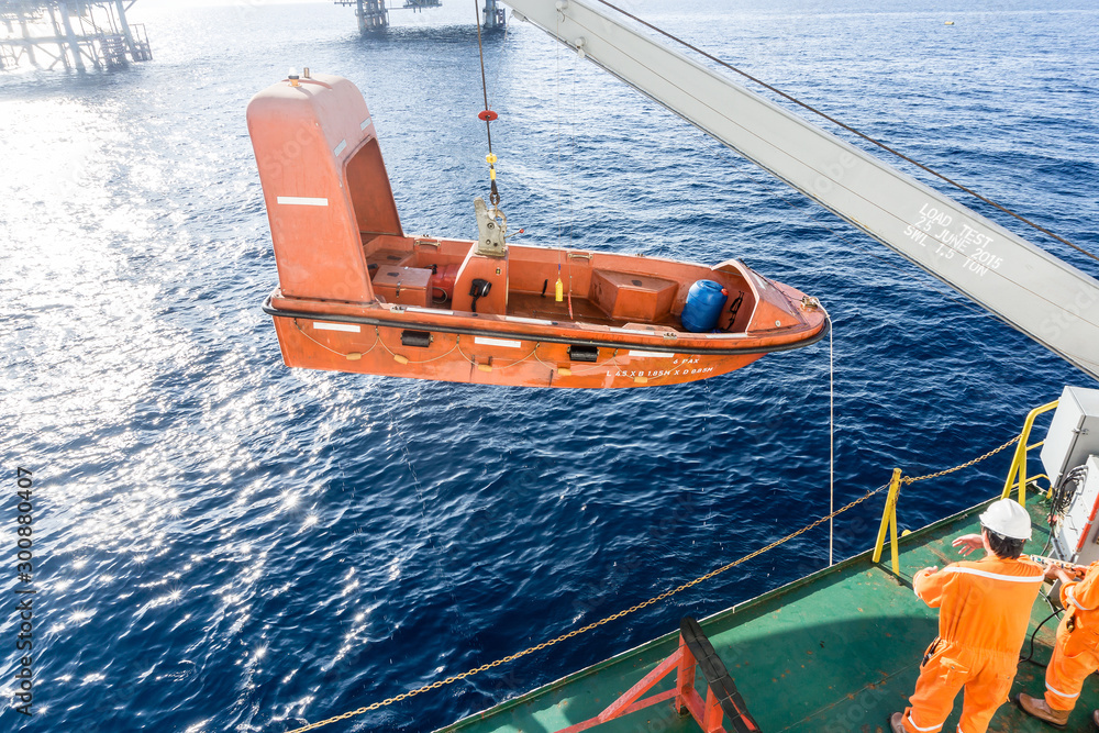 Fast rescue craft being hoisted onto a construction barge after ...
