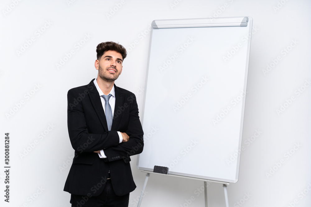 Young businessman giving a presentation on white board looking up while smiling Young businessman giving a presentation on white board looking up while smiling