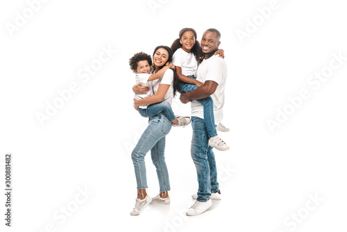 happy african american woman holding son, and husband holding daughter on white background