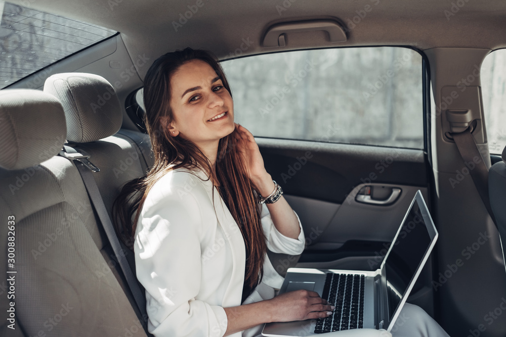 Fashion Stylish Girl in White Suit Works at Laptop in Car Fashion Stylish Girl in White Suit Works at Laptop in Car